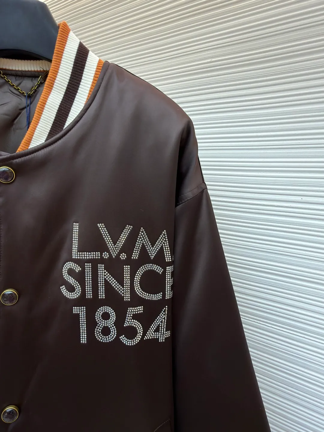 LOUIS VUITTON decorative flight jacket ●Original version: 30,000 purchased and developed ●Item number: 1682285-B90 ●Fabric: cotton fabric ●Technology: patch production ●Color: brown ●Version: fitted version ●Weight: about 1085 grams ●Size: 46-48-50-52 ●Description: The main body of this Louis Vuitton satin baseball jacket is made of high-density matte satin fabric, which has been treated with anti-wrinkle shaping technology. The fabric has a strong drape and is not easy to wrinkle. The dark brown background color is prepared by precision dyeing and finishing technology, giving it a rich color and high-end texture. The "L.V.M SINCE 1854" logo on the left chest is made with hot-drilling technology. High-quality rhinestones are used for precise hot-pasting in different areas. The diamond surface is shiny and strong and will not fall off easily. The ribbed splicing of the collar, cuffs and hem is a three-color contrasting design. It is woven with high-elastic knitted yarn, which will not easily loosen and deform after long-term wear. The placket is equipped with custom-made metal snaps. The hardware is thick and anti-oxidation. The overall style is loose and off-shoulder. The splicing is covered with blind stitching technology, and the wiring is smooth and traceless. Every craft detail follows the brand's luxury product production standards, taking into account both design and wearing comfort. The overall wiring is straight and delicate, the fabric is comfortable and soft, and the color is consistent without color difference. It can be matched with the same style to create a fashionable look and control various occasions. Customized accessories, complete with three standards, same style for men and women!